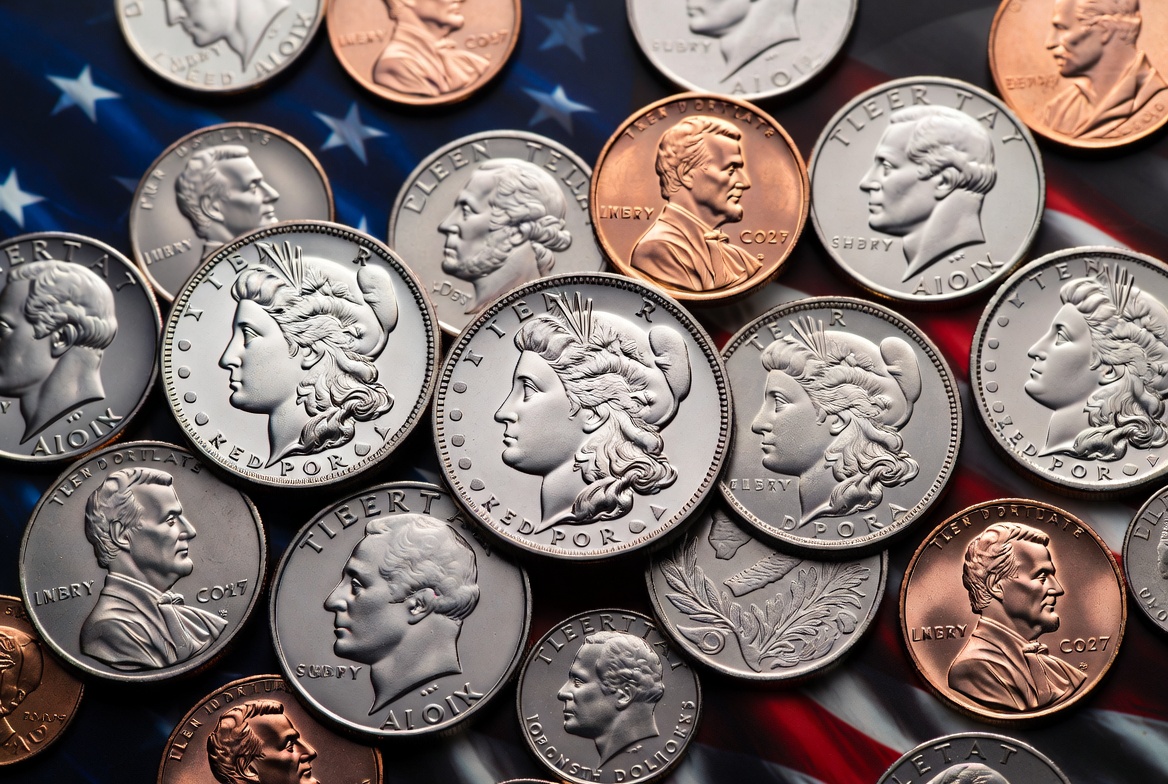 Morgan silver dollars, gold and copper coins arranged on an American flag